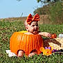 baby, pumpkin, orange_bow, grass, outdoor, hay_bale, toy, mickey_mouse, autumn, smiling, child, cute, festive, nature, sunlight, hollow_pumpkin, playful, holiday, decoration, field
