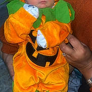 Layton joined the competition — help win amazing prizes! baby, costume, pumpkin, orange, green, sleeping, infant, hands, cute, holiday, halloween, child, clothing, person, indoor, soft_fabric, adorable, resting, face, holding