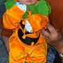baby, costume, pumpkin, orange, green, sleeping, infant, hands, cute, holiday, halloween, child, clothing, person, indoor, soft_fabric, adorable, resting, face, holding