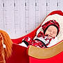 Layton is registered to the contest to win money with this photo: baby, sleeping, pajamas, red, black, reindeer, sleigh, blanket, plush_toy, horse, wooden_background, festive, cozy, child, infant, holiday, indoor, cute, resting, soft