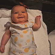 Marceline is registered to the contest to win money with this photo: baby, infant, smiling, onesie, pineapple_pattern, headband, bow, reflection, mirror, towel, white, cute, happy, child, indoors, portrait, skin, lying_down, arm, hand