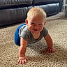 baby, crawling, carpet, indoor, smiling, child, blonde_hair, leather_couch, playpen, home, floor, cute, person, young_child, happy, toddler, casual_clothing, gray_shirt, blue_pants, living_room