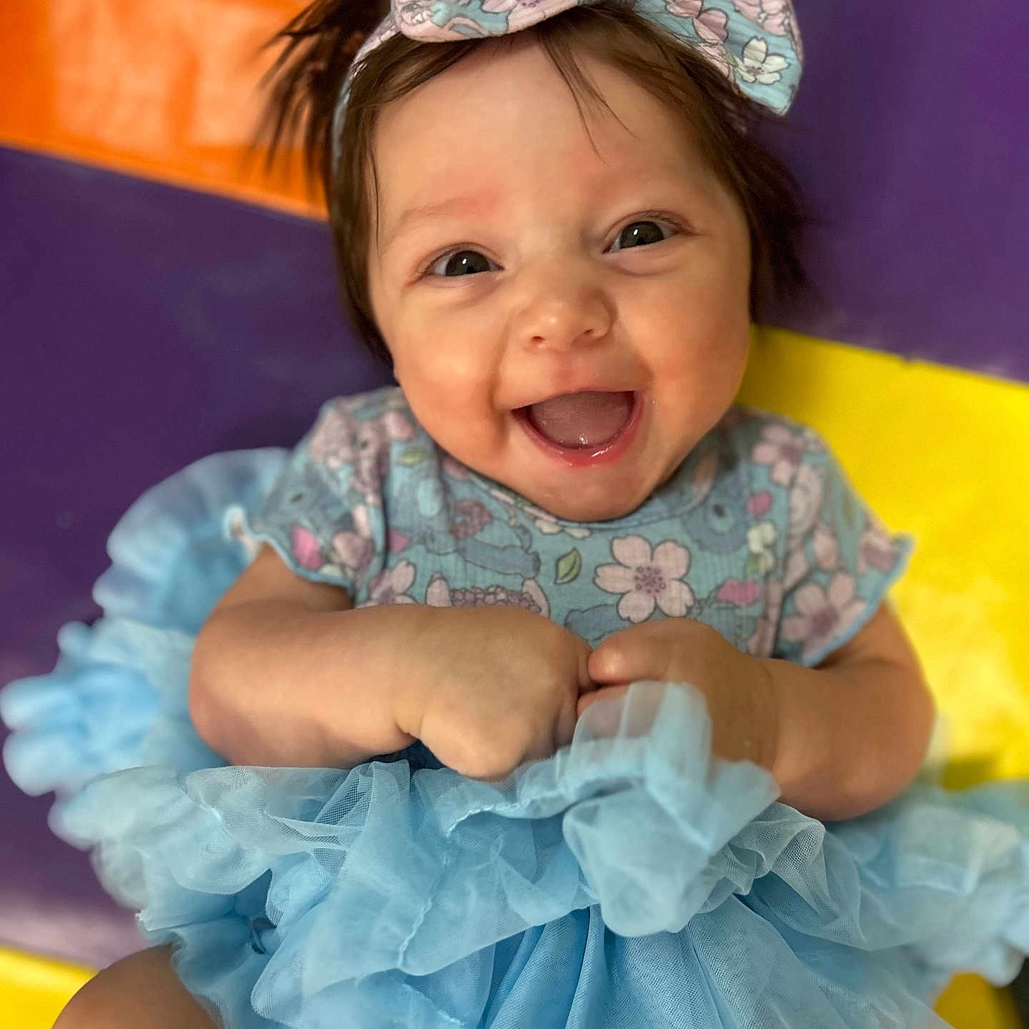 Emry is registered to the contest to win money with this photo: baby, blue, bow, child, colorful_background, cute, dress, face, floral, hands, happy, infant, joy, mat, person, portrait, sitting, smiling, tulle, young