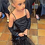 child, girl, black_dress, gloves, long_hair, ponytail, indoor, tiled_floor, people, seated_adults, formal_wear, event, hands, legs, shoes, floor, expression, portrait, fashion, waiting