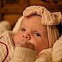 Kennedy is registered to the contest to win money with this photo: baby, infant, headband, bow, blanket, knitwear, closeup, face, hand, curious, warm, soft_lighting, portrait, indoors, child, cute, cozy, skin, expression, resting
