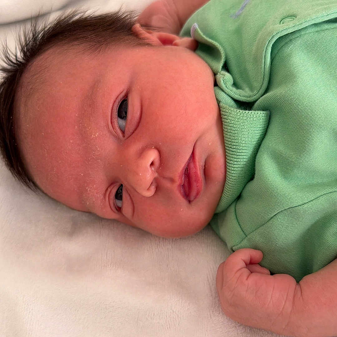Yeshua joined the competition — help win amazing prizes! newborn, baby, infant, sleepy, portrait, face, eyes, hair, green_outfit, onesie, blanket, lying_down, indoor, close_up, head, arm, hand, soft_lighting, baby_skin, cozy