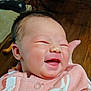 Blakely is registered to the contest to win money with this photo: baby, newborn, infant, smiling, face, cheeks, mouth, eyes_closed, hand, supporting_hand, pink_clothing, onesie, blanket, hair, skin, portrait, close_up, indoors, wood_floor, happy