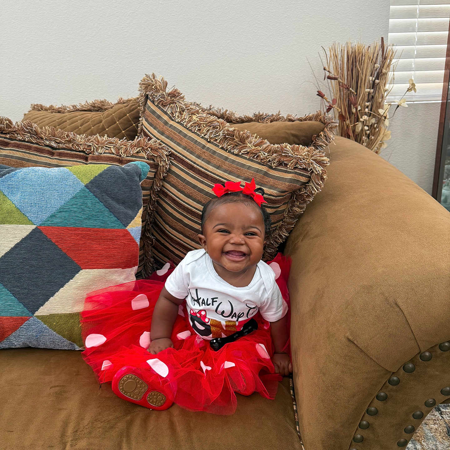 Carmyn joined the competition — help win amazing prizes! baby, child, clothing, couch, cute, decor, fashion, footwear, happy, home_interior, indoor, infant, person, pillow, portrait, red_bow, sitting, smiling, tutu, window_blinds