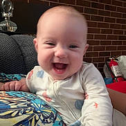 Eleanor is registered to the contest to win money with this photo: baby, brick_wall, child, colorful, cozy, cushion, cute, face, fire_extinguisher, hand, happy, head, indoor, infant, joyful, onesie, patterned, person, portrait, smiling