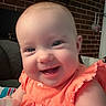 Eleanor joined the competition — help win amazing prizes! apparel, baby, brick_wall, cheerful, child, closeup, cute, face, happy, head, indoor, infant, orange_clothing, person, portrait, sitting, skin, smiling, toddler, young