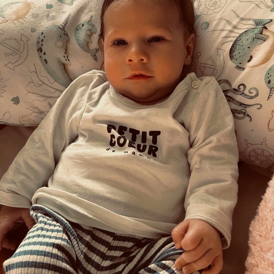 Mayann a rejoint le concours — aidez-le/la à gagner de superbes lots ! baby, bedding, child, cozy, cuddly, cute, eyes, face, hair, hand, indoors, infant, nautical_pattern, onesie, pillow, portrait, sleepy, sock, soft_lighting, striped_pants