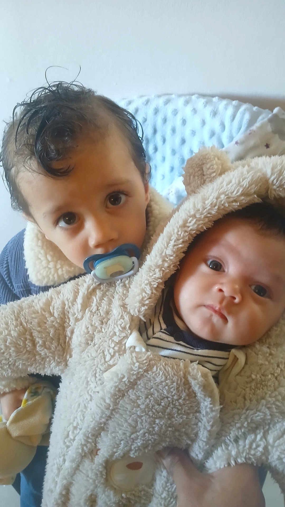 Soânn participe au concours pour gagner de l'argent avec cette photo : baby, bear_ears, blanket, child, coat, cuddly, curly_hair, cute, face, fluffy, hand, indoor, pacifier, person, portrait, siblings, soft_texture, striped_clothing, toddler, warm_clothing