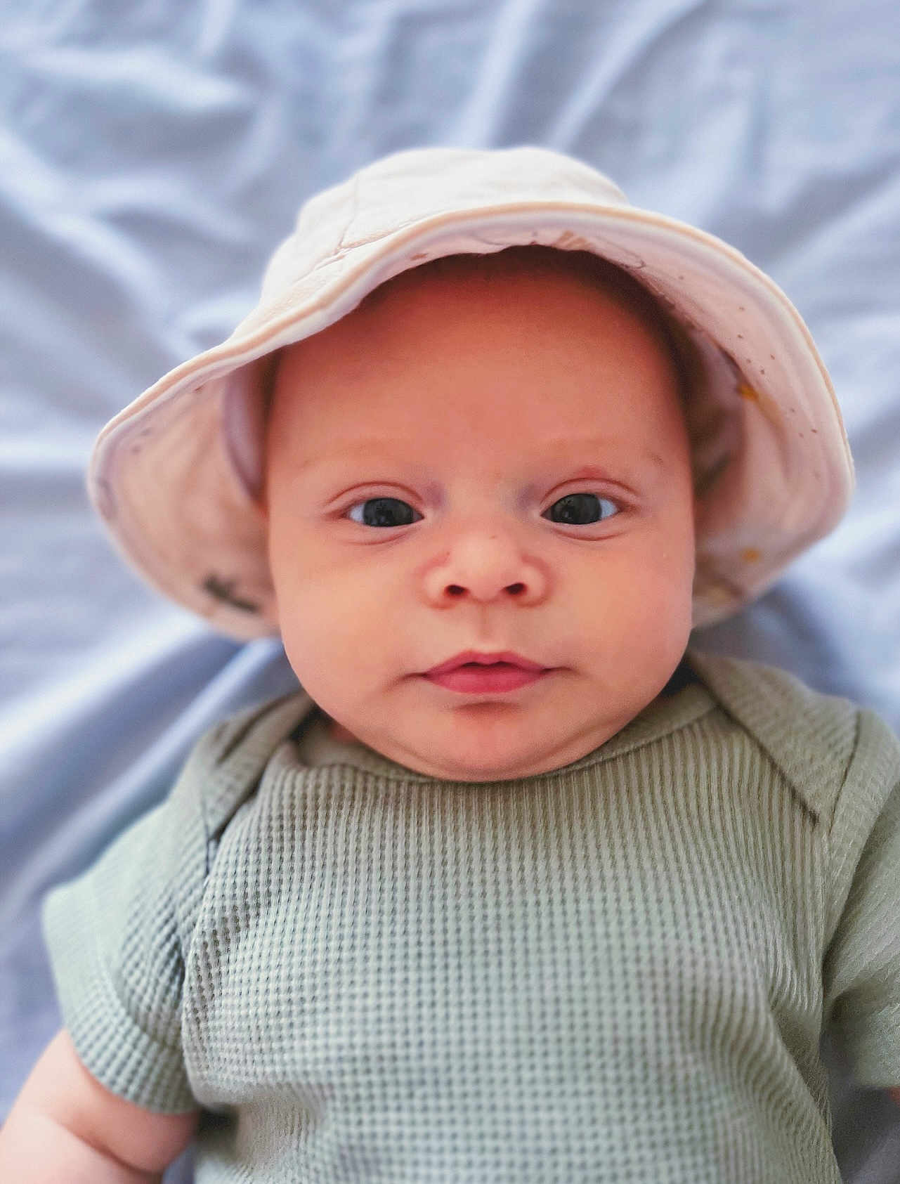 Malakai is registered to the contest to win money with this photo: baby, bonnet, cap, clothing, face, hat, head, hood, newborn, person, photography, portrait, sunhat