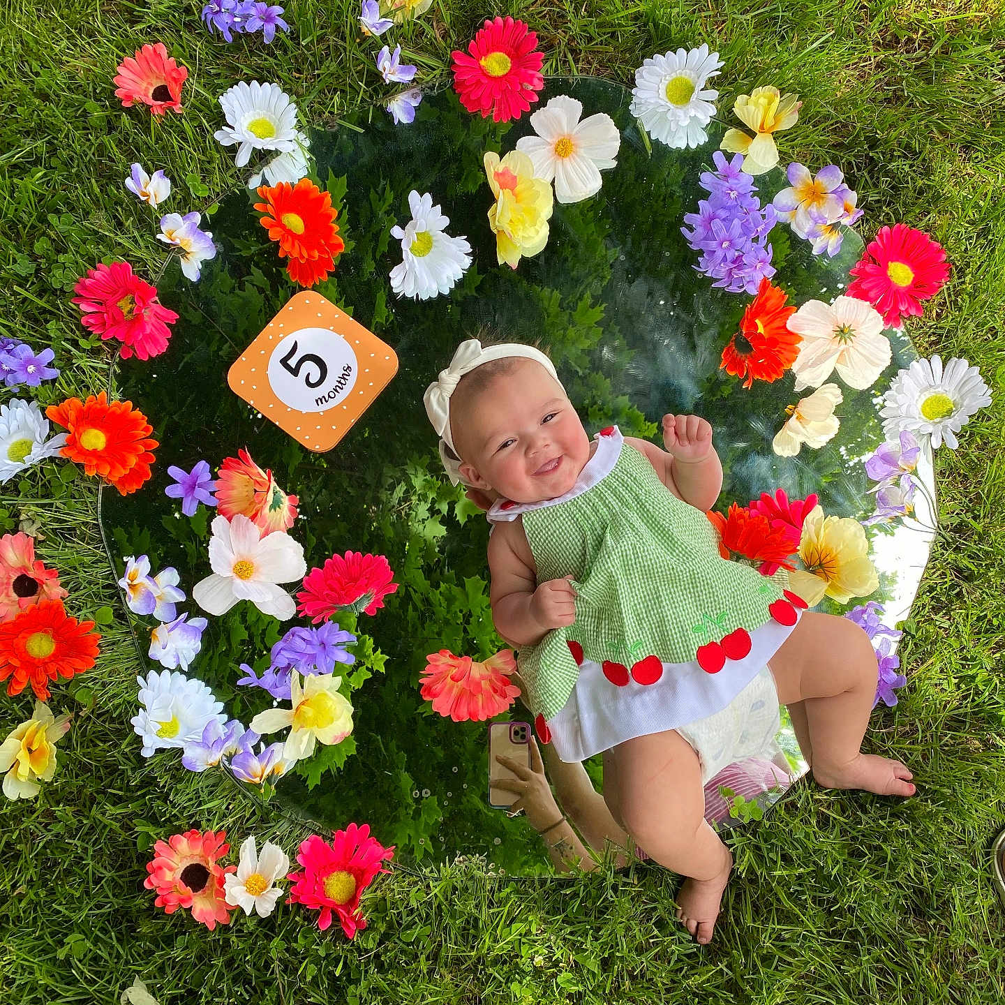 Noralia joined the competition — help win amazing prizes! baby, celebration, colorful, cute, feet, flowers, grass, green_dress, hand, headband, infant, milestone_card, mirror, nature, outdoor, person, photography, reflection, smiling, summer