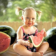 Liala joined the competition — help win amazing prizes! child, toddler, watermelon, fruit, summer, outdoor, pigtails, eating, happy, cute, sitting, food, snack, playful, nature, greenery, fence, daylight, portrait, smiling
