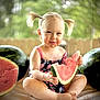 child, toddler, watermelon, fruit, summer, outdoor, pigtails, eating, happy, cute, sitting, food, snack, playful, nature, greenery, fence, daylight, portrait, smiling