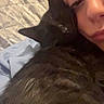 cat, black_cat, person, face, portrait, cuddling, bed, bedroom, indoor, selfie, close_up, fur, whiskers, ears, sleepy, snuggling, pet, companion, blanket, cozy