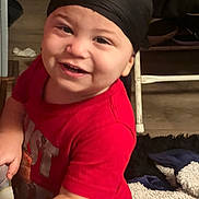 Xion is registered to the contest to win money with this photo: baby, blanket, carpet, child, clothing, cozy, cute, face, floor, furniture, happy, head_wrap, home, indoor, person, playful, portrait, red_shirt, smiling, toddler