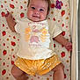 baby, infant, smiling, child, cute, blanket, strawberry_pattern, tshirt, shorts, pacifier, toy, lying_down, happy, indoors, person, face, skin, head, arm, leg