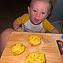 Izayah joined the competition — help win amazing prizes! toddler, child, food, snack, cutting_board, curious, indoor, yellow_shirt, face, expression, kitchen, plate, hand, table, person, eyes, mouth_open, light, floor, background