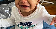 Annalise joined the competition — help win amazing prizes! baby, smiling, sitting, indoor, clothing, pacifier, blanket, face, person, happy, headwear, toy, nike, pants, floor, fan, room, hair, child, expression