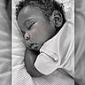 baby, sleeping, curly_hair, blanket, striped, black_and_white, infant, peaceful, soft_lighting, portrait, closeup, child, resting, cute, toddler, face, clothing, bed, indoors, calm