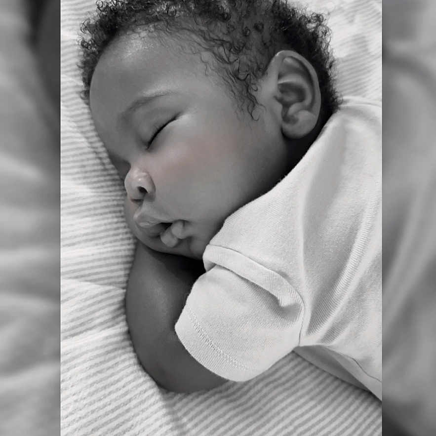 Nore joined the competition — help win amazing prizes! baby, sleeping, curly_hair, blanket, striped, black_and_white, infant, peaceful, soft_lighting, portrait, closeup, child, resting, cute, toddler, face, clothing, bed, indoors, calm