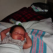Kyra is registered to the contest to win money with this photo: newborn, baby, sleeping, infant, portrait, face, bed, blanket, bedding, bottle, nursery, indoors, cozy, resting, arms_up, curly_hair, closed_eyes, patterned_fabric, photography, child