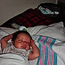 newborn, baby, sleeping, infant, portrait, face, bed, blanket, bedding, bottle, nursery, indoors, cozy, resting, arms_up, curly_hair, closed_eyes, patterned_fabric, photography, child