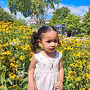 Lise a rejoint le concours — aidez-le/la à gagner de superbes lots ! child, girl, flower_garden, yellow_flowers, white_dress, curly_hair, pigtails, outdoor, nature, sunny, greenery, portrait, summer, blue_sky, trees, necklace, young, innocent, daylight, plants