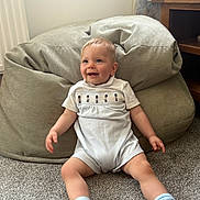 Jack joined the competition — help win amazing prizes! baby, child, smiling, sitting, carpet, bean_bag, indoor, white_clothing, socks, wooden_furniture, curtain, tassel, happy, person, floor, cute, infant, cozy, home, portrait