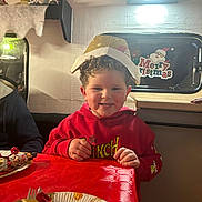 Nill a rejoint le concours — aidez-le/la à gagner de superbes lots ! celebration, child, christmas_decorations, curly_hair, festive, food, fork, grinch, happy, holiday, holiday_hat, indoor, merry_christmas_sign, party, person, plate, red_hoodie, red_tablecloth, smiling, table