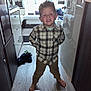 Nill participe au concours pour gagner de l'argent avec cette photo : child, boy, smile, barefoot, plaid_shirt, pants, hallway, floor, window, curtains, clothing, indoor, furniture, door, cabinet, wood_floor, person, portrait, happy, curly_hair