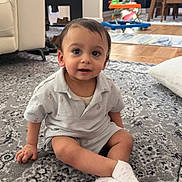 Amir is registered to the contest to win money with this photo: toddler, child, baby, indoor, carpet, socks, sitting, smiling, person, home, furniture, toy, curious, floor, eyes, clothing, portrait, living_room, couch, white