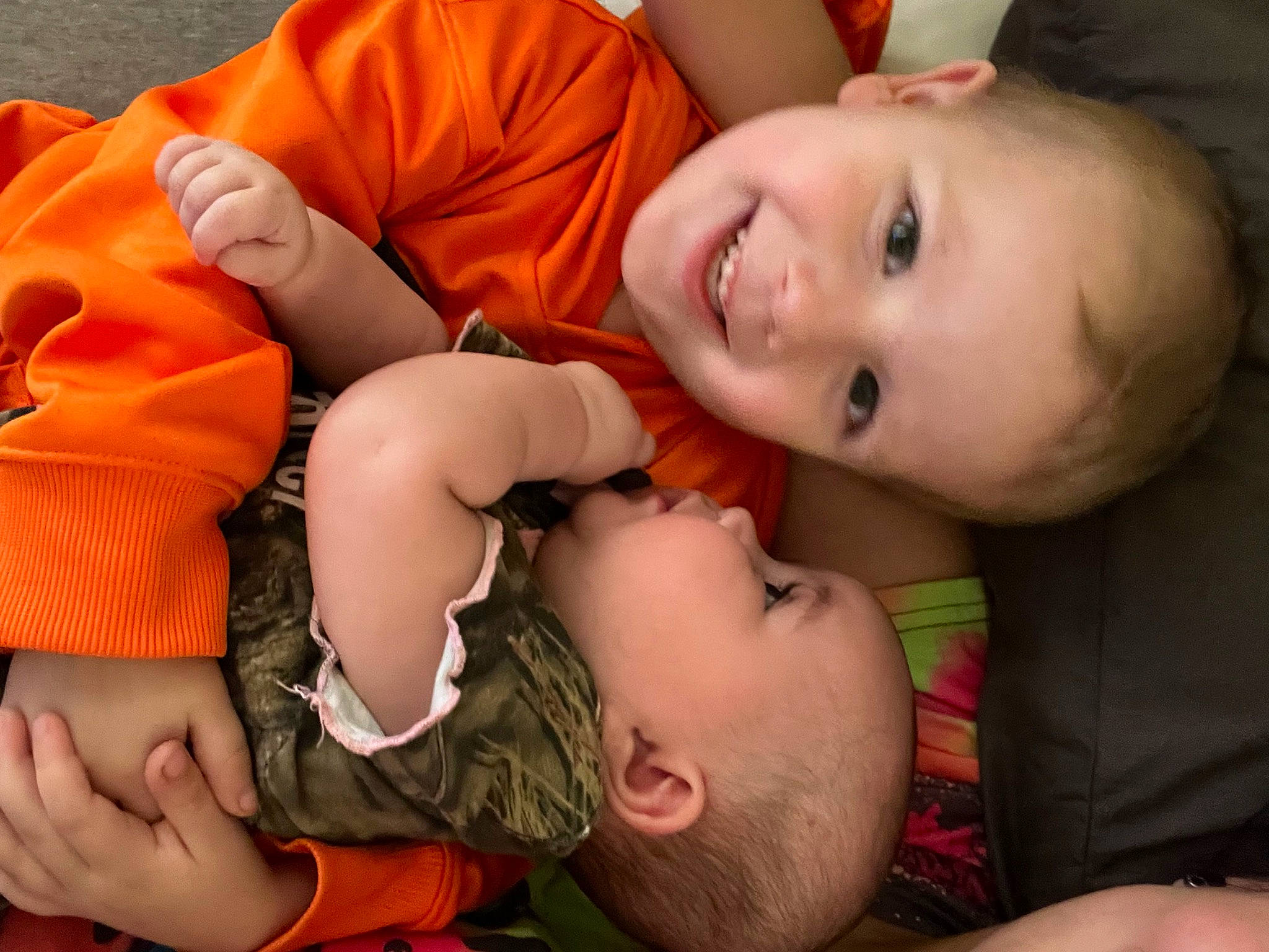 Oaklee is registered to the contest to win money with this photo: abdomen, arm, baby, baby_toddler_clothing, cheek, finger, grass, green, happy, human_body, iris, joy, mouth, muscle, nose, orange, organ, person, skin, smile