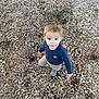 Tunney is registered to the contest to win money with this photo: child, toddler, wood_chips, outdoor, curious, standing, blue_shirt, beige_pants, fox_emblem, casual_clothing, nature, playground, young_child, looking_up, person, daylight, ground_cover, boots, short_hair, cute