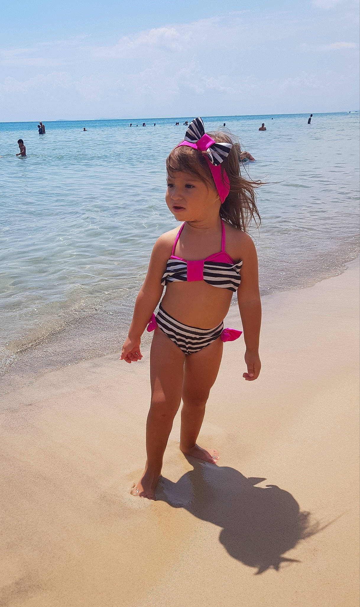 Meryam participe au concours pour gagner de l'argent avec cette photo : barefoot, beach, bikini, child, coast, fun, headwear, leg, long_hair, ocean, people_on_beach, person, pink, sand, sea, stomach, summer, swimsuit_top, swimwear, undergarment