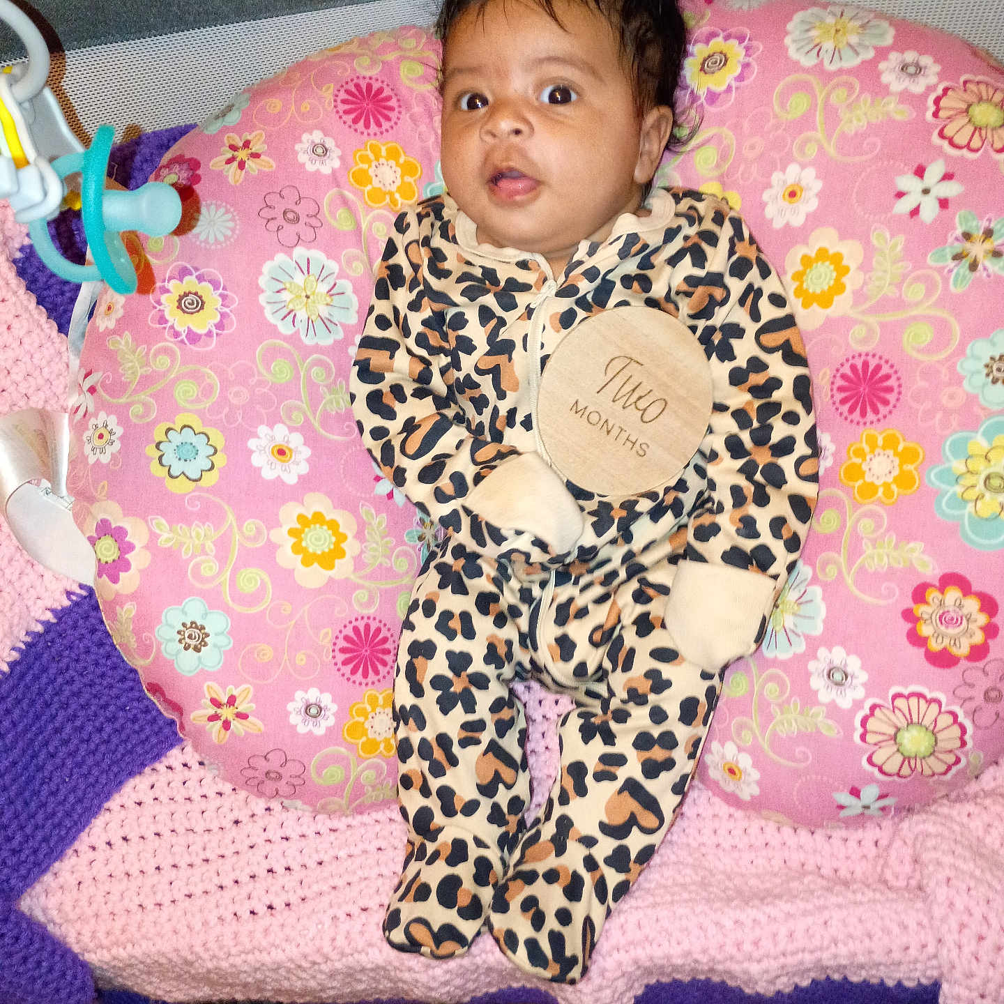 Daliha joined the competition — help win amazing prizes! baby, baby_toy, carpet, child, clothing, crocheted_blanket, cute, face, floral_pattern, indoor, infant, leopard_print, lying_down, newborn, onesie, person, pillow, pink, purple, wide_eyes