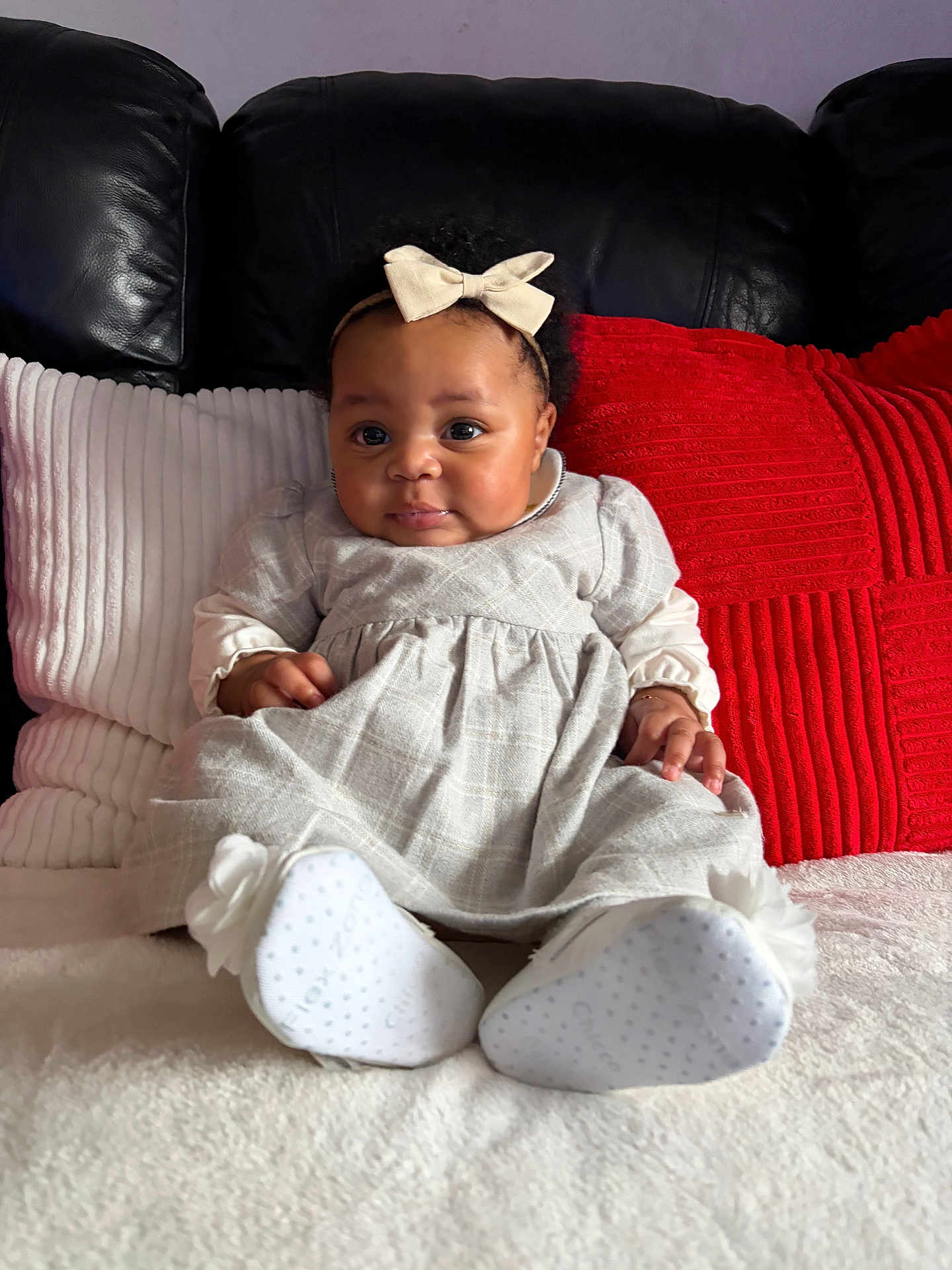 Madyson a rejoint le concours — aidez-le/la à gagner de superbes lots ! baby, bow, child, couch, cute, dress, face, flower, footwear, headband, indoors, infant, person, pillow, portrait, red, seated, shoes, sofa, white