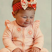 Lilyana joined the competition — help win amazing prizes! baby, child, infant, onesie, headband, bow, orange, peach, floral_pattern, sitting, smiling, cute, portrait, chubby_cheeks, hands, long_sleeves, comfortable, soft_lighting, studio_photo, innocence