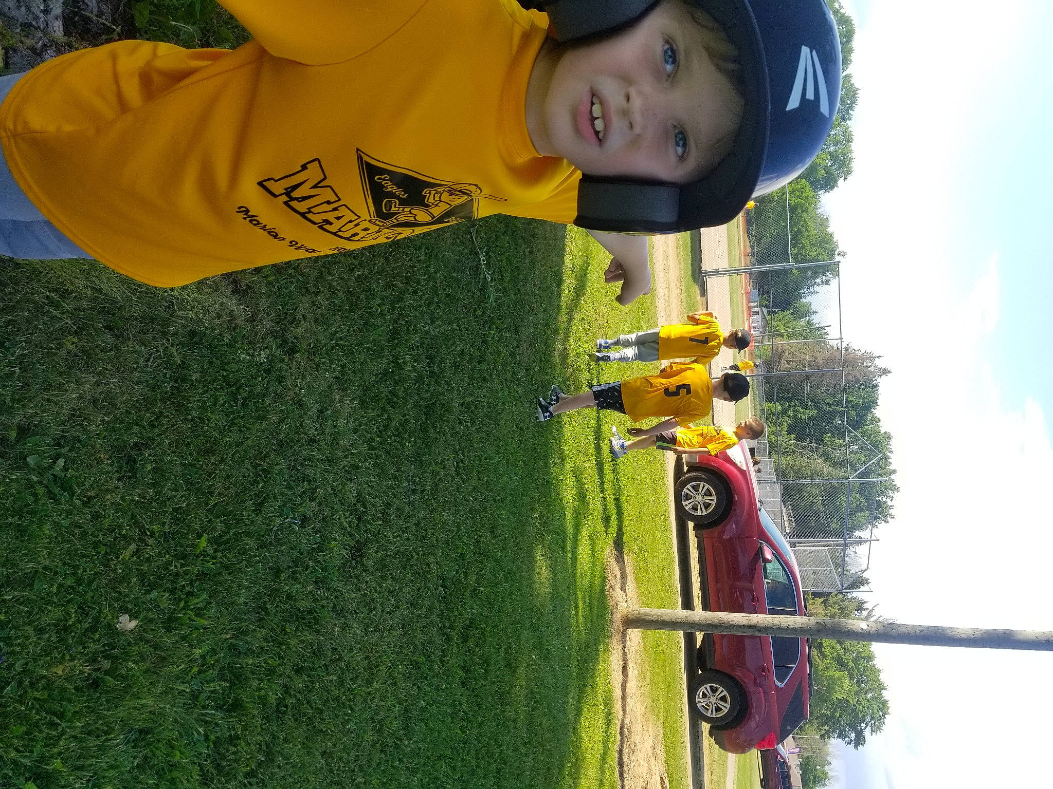 Donovan is registered to the contest to win money with this photo: automotive_exterior, automotive_lighting, automotive_tire, car, cloud, grass, hat, headwear, leisure, motor_vehicle, person, plant, recreation, sky, sports_equipment, t_shirt, tire, toddler, tree, vehicle