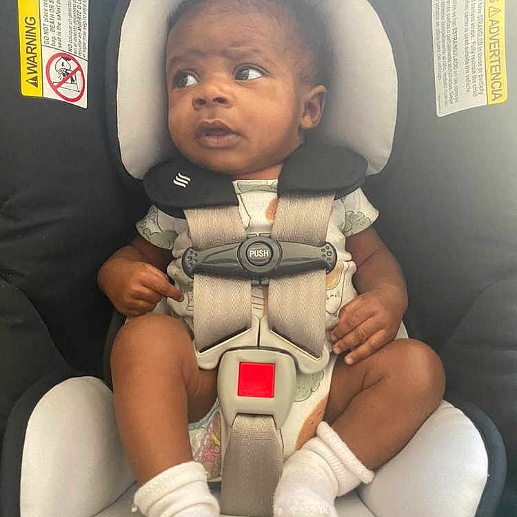 Kyrie is registered to the contest to win money with this photo: baby, car, car_interior, carseat, clothing, coat, cushion, face, furniture, head, homedecor, hosiery, jacket, person, photography, portrait, sitting, sock, transportation, vehicle