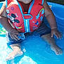 toddler, child, life_jacket, pool, water, sitting, smiling, toy, outdoor, summer, cute, mickey_mouse, playful, wet_hair, blue, red, grass, sunlight, barefoot, happy