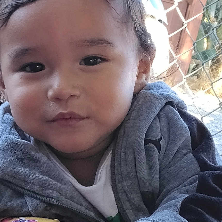 Lisandro Mendez joined the competition — help win amazing prizes! casual_clothing, child, close_up, curly_hair, cute, daylight, expression, eye_contact, face, fence, gray_clothing, hand, jacket, nature, outdoor, person, portrait, smile, toddler, young_child