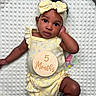 Island joined the competition — help win amazing prizes! baby, infant, child, yellow_outfit, headband, milestone, wooden_sign, blanket, textured_blanket, curly_hair, portrait, cute, lying_down, hand_near_face, expression, indoor, soft_lighting, closeup, people, newborn