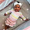 baby, bow, child, colorful_clothing, cozy, cute, happy, headband, indoor, infant, lying_down, moon_pattern, pink_shorts, playpen, smiling, socks, soft_toys, star_pattern, striped_shirt, tongue_out
