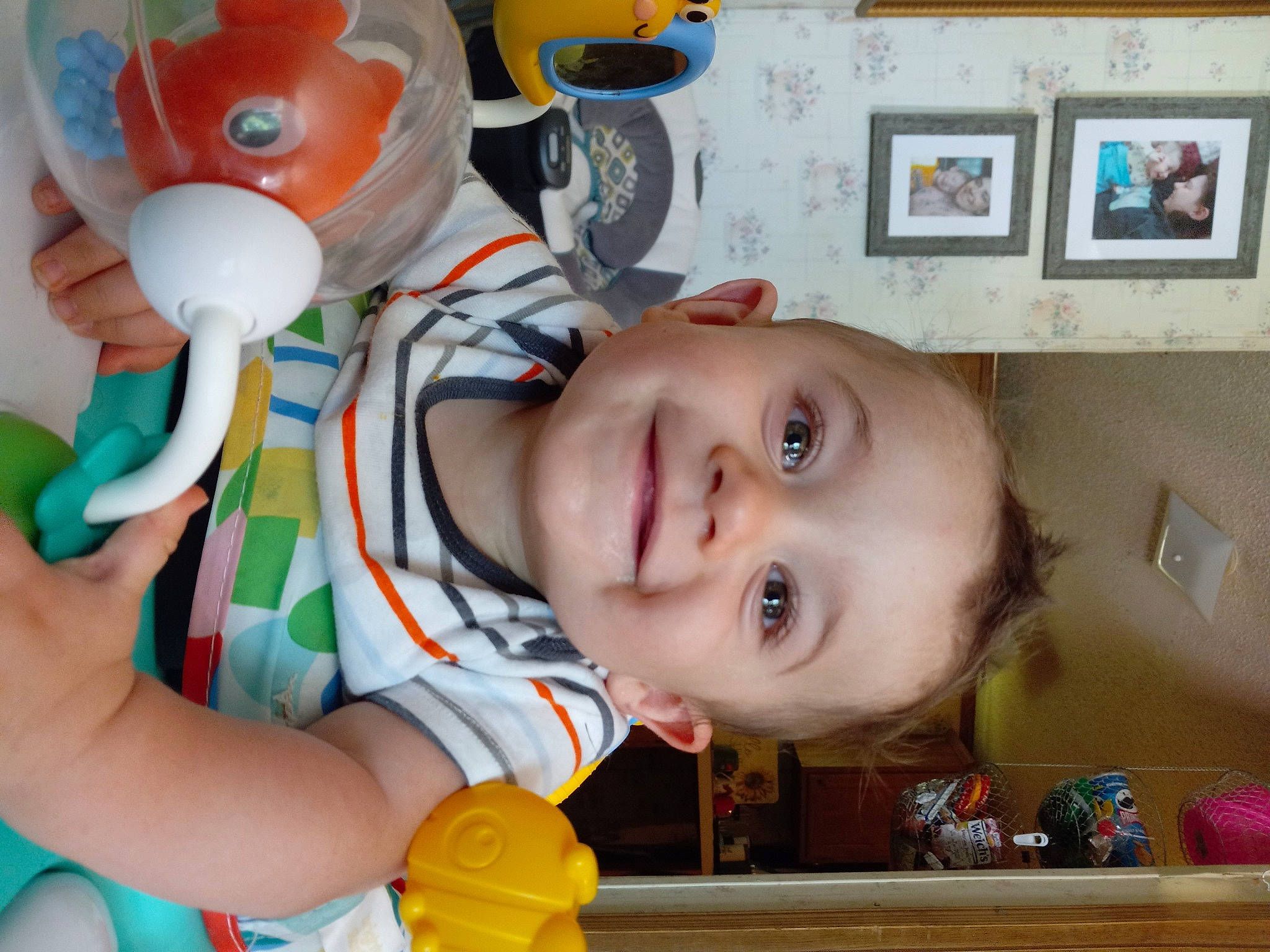 Jenson is registered to the contest to win money with this photo: baby, baby_products, baby_toddler_clothing, baby_toys, blurred, cheek, child, fun, happy, joy, nose, orange, organ, person, picture_frame, play, room, shelf, smile, toddler