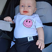 Rilynn is registered to the contest to win money with this photo: baby, infant, smiling, blue_eyes, white_shirt, smiley_face, stroller, black_pants, cute, happy, child, clothing, hand, face, portrait, seated, young, casual, baby_clothes, expression