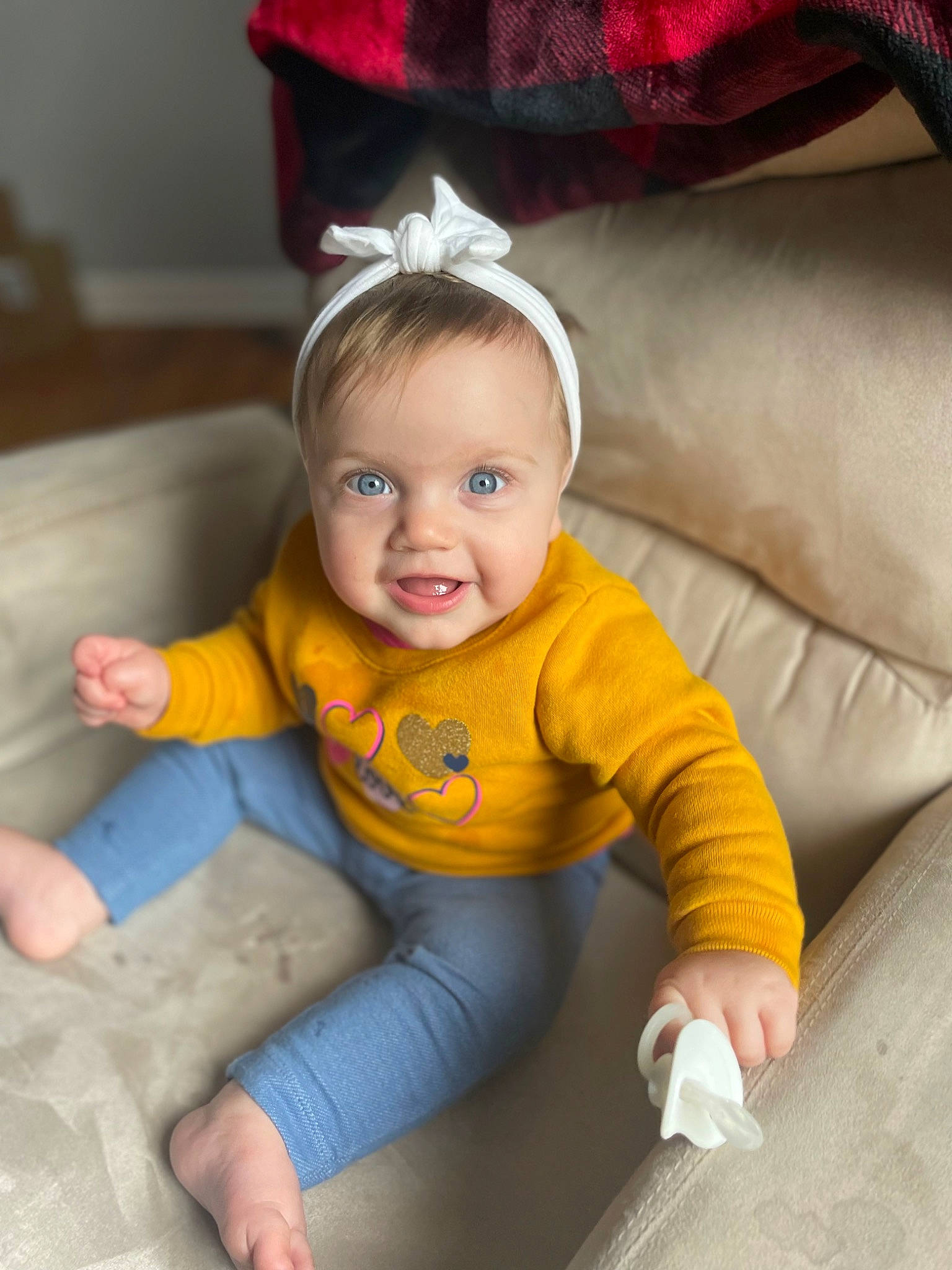 Della is registered to the contest to win money with this photo: baby, baby_toddler_clothing, child, comfort, costume_hat, eye, flooring, fun, hair, happy, head, human_body, iris, person, product, red, sitting, skin, sleeve, smile