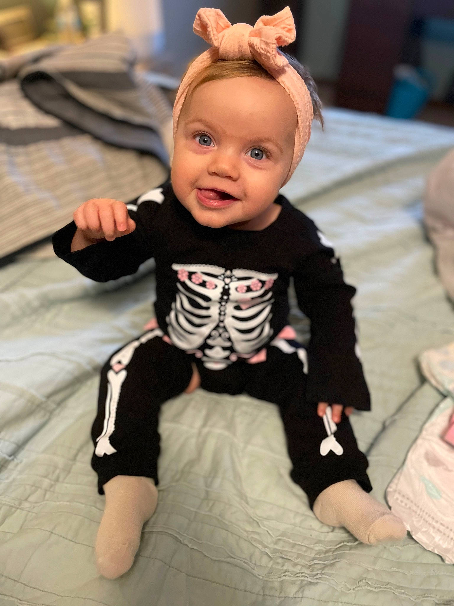 Della is registered to the contest to win money with this photo: baby, baby_toddler_clothing, cheek, child, comfort, eye, flooring, fun, happy, head, linens, pattern, person, sitting, skin, sleeve, smile, t_shirt, textile, toddler